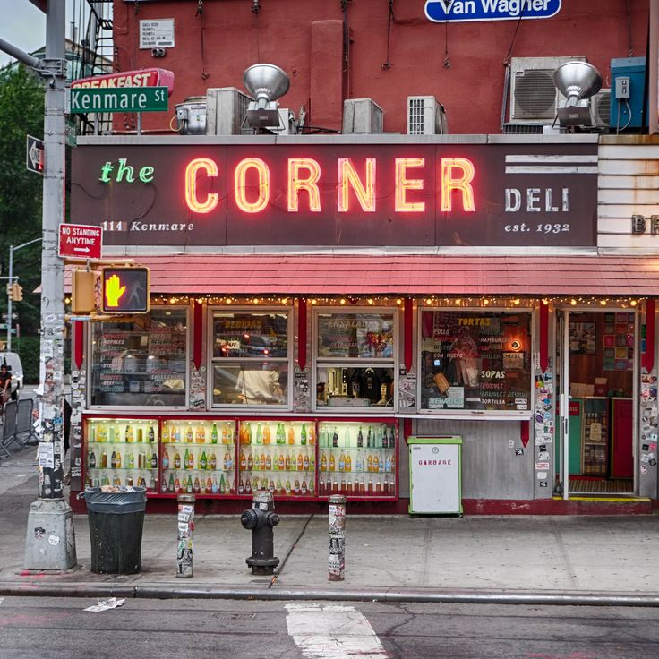 a corner deli with neon signs on the side of it's storefront