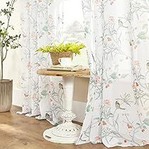 the curtains in this room are white and have flowers on them, along with a potted plant