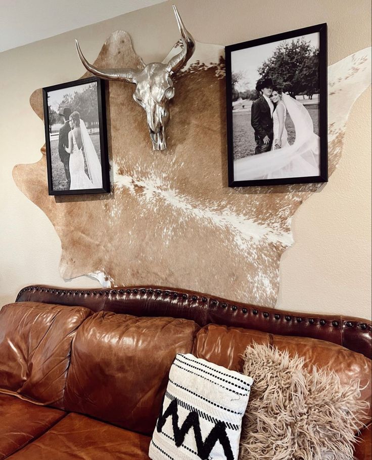 a couch with two pictures on the wall and a cow skull mounted to it's side