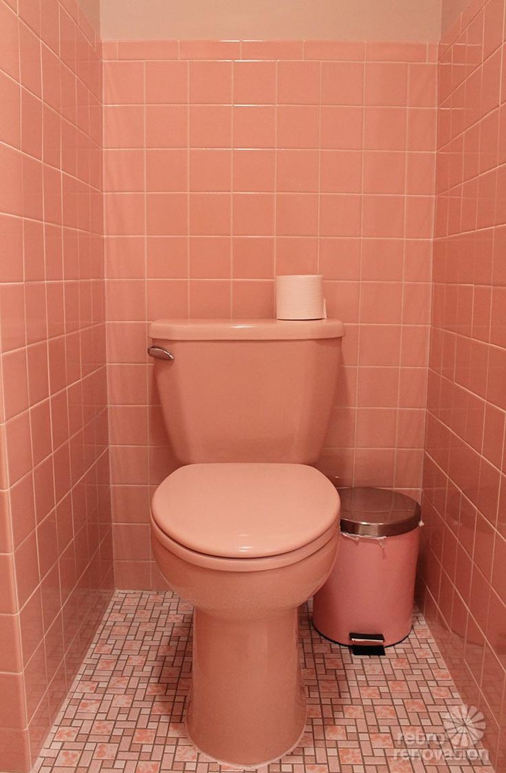 a pink toilet sitting in a bathroom next to a trash can on a tiled floor