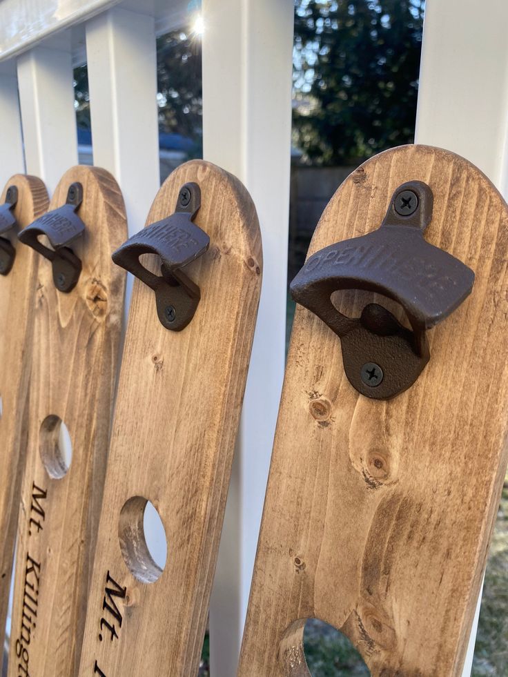 three wooden boards with bells on them sitting in front of a white picket fence outside