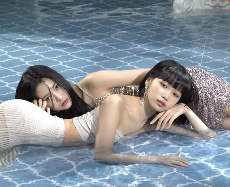 two young women laying on the ground next to each other in an indoor swimming pool