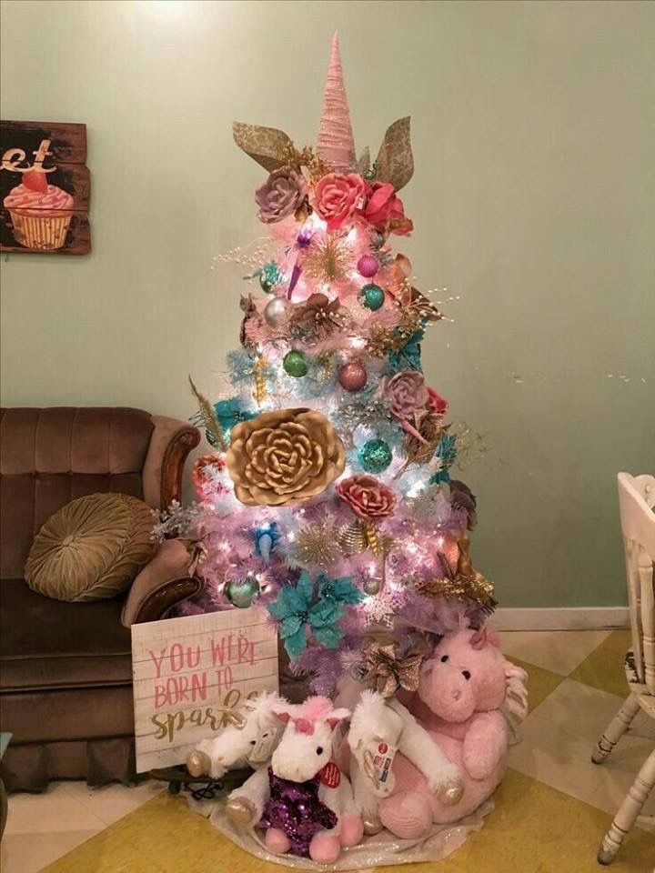 a pink and blue christmas tree with lots of stuffed animals on the bottom, sitting in front of a brown chair