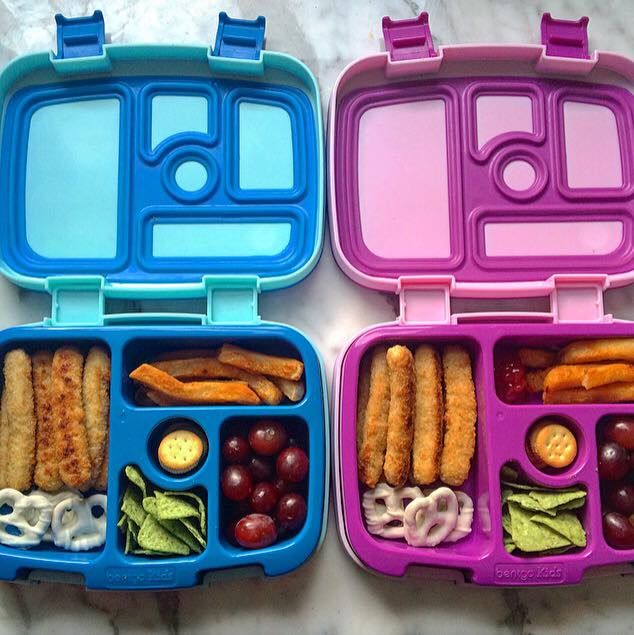 two plastic lunch boxes filled with food on top of a marble countertop next to each other