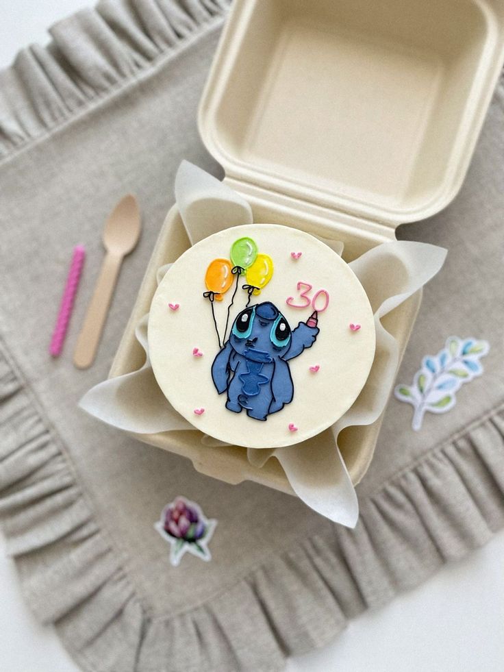 a decorated cookie in the shape of an elephant with balloons on it sitting next to a fork and spoon