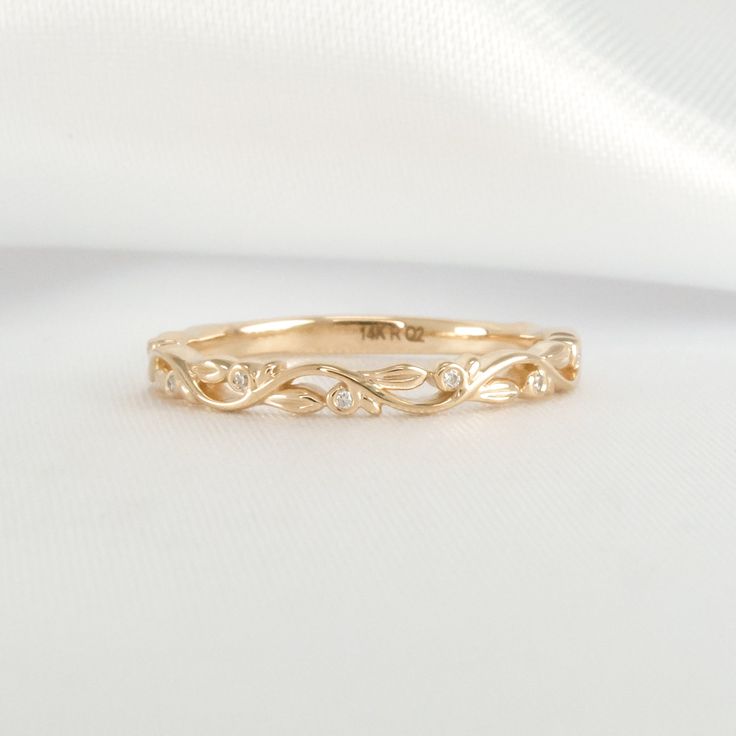 a yellow gold wedding band with three diamonds on the top and bottom, sitting on a white cloth