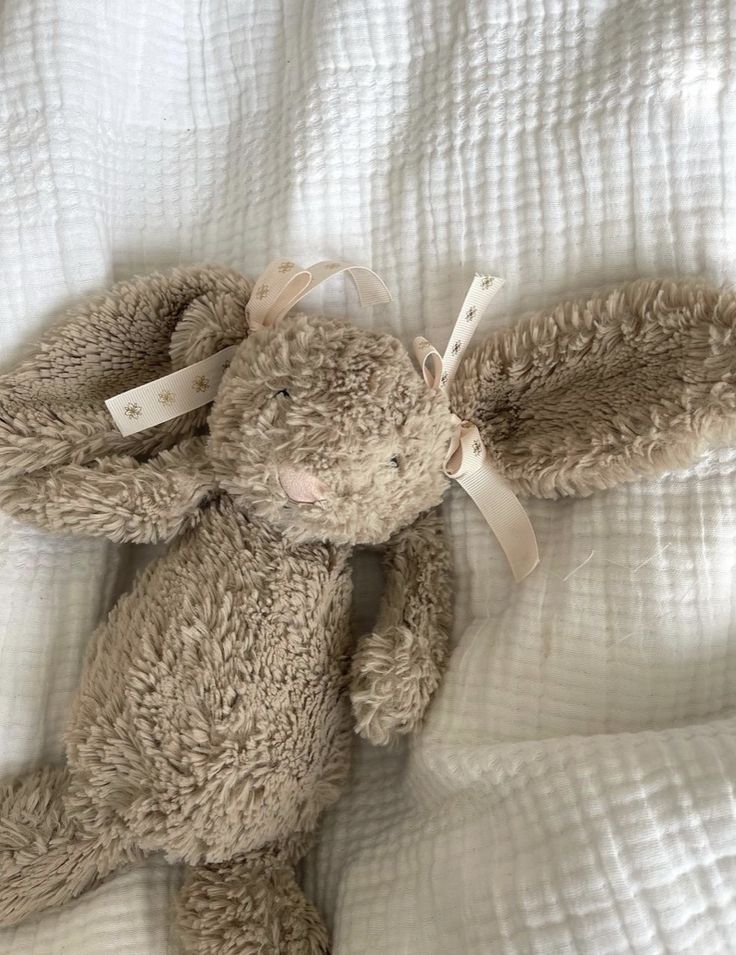 a brown teddy bear laying on top of a bed