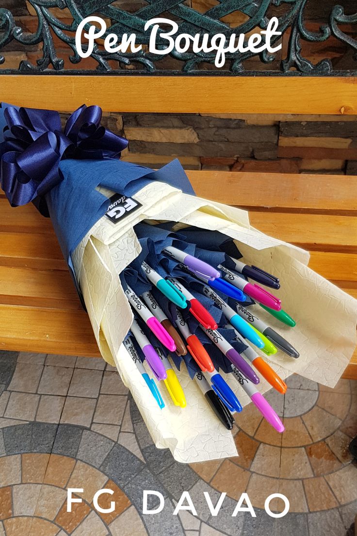 a bunch of pens sitting on top of a wooden bench next to a blue ribbon