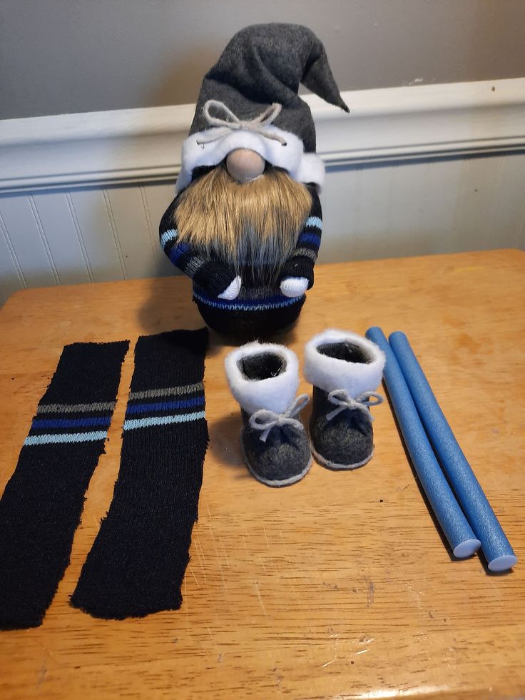 a wooden table topped with two pairs of slippers and a doll's hat