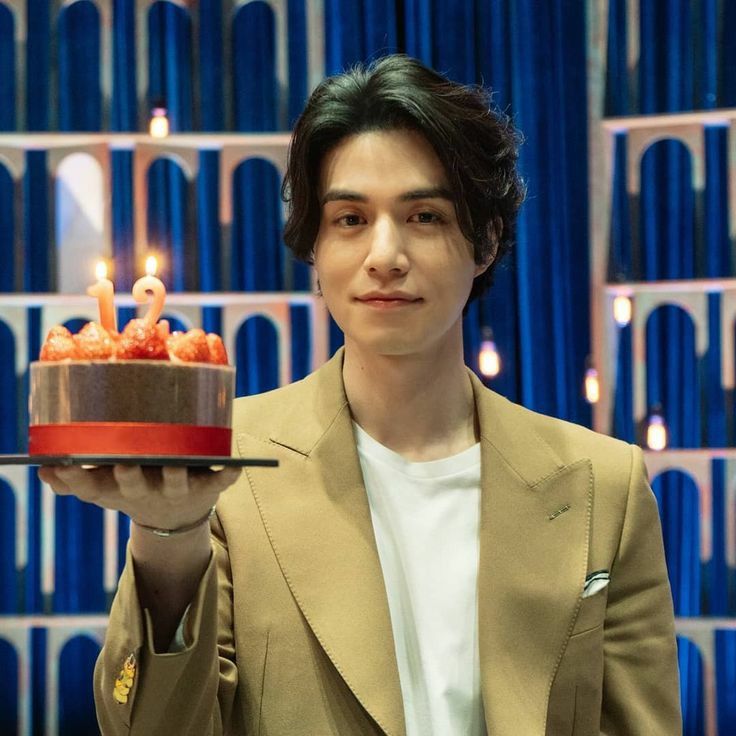 a man holding a cake with candles on it