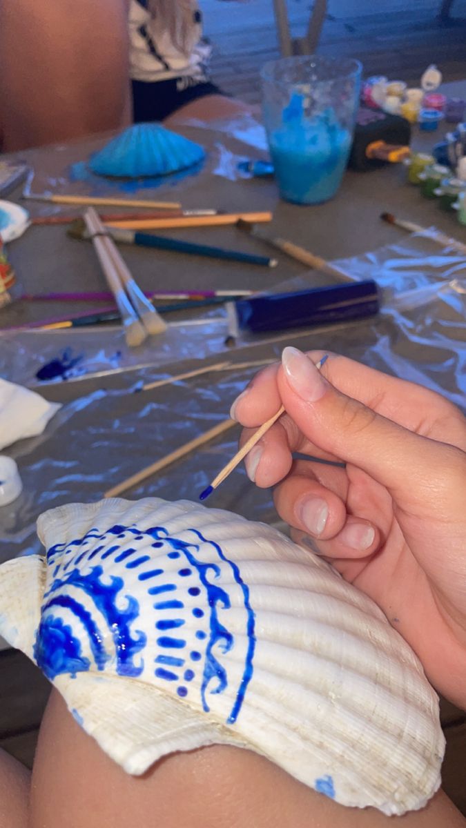 someone is painting shells on the table with paintbrushes