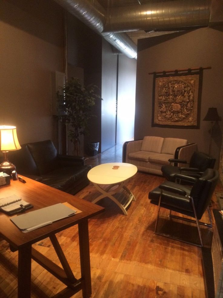 a living room filled with furniture and a wooden table in front of a lamp on top of a hard wood floor