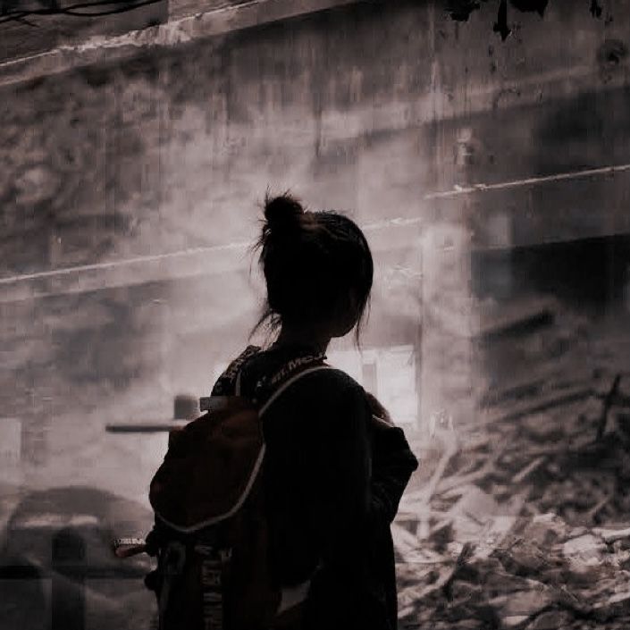 a person with a back pack standing in front of a building that has been destroyed