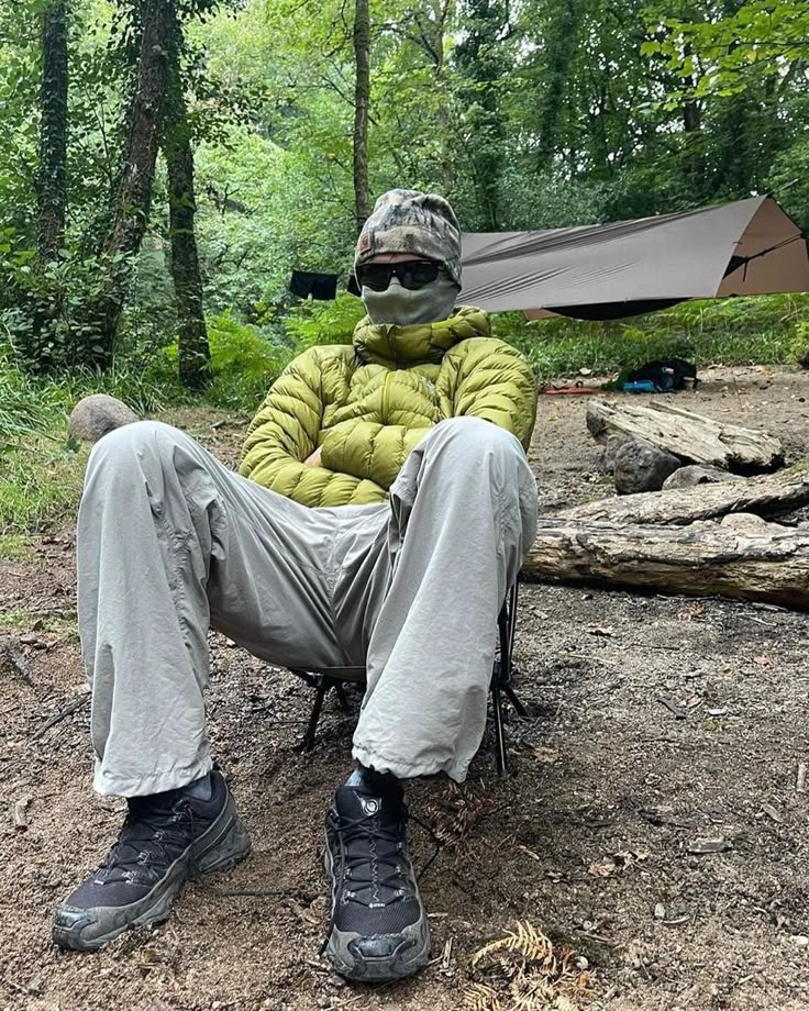 a man sitting in a camping chair with his feet up on the ground next to a tent