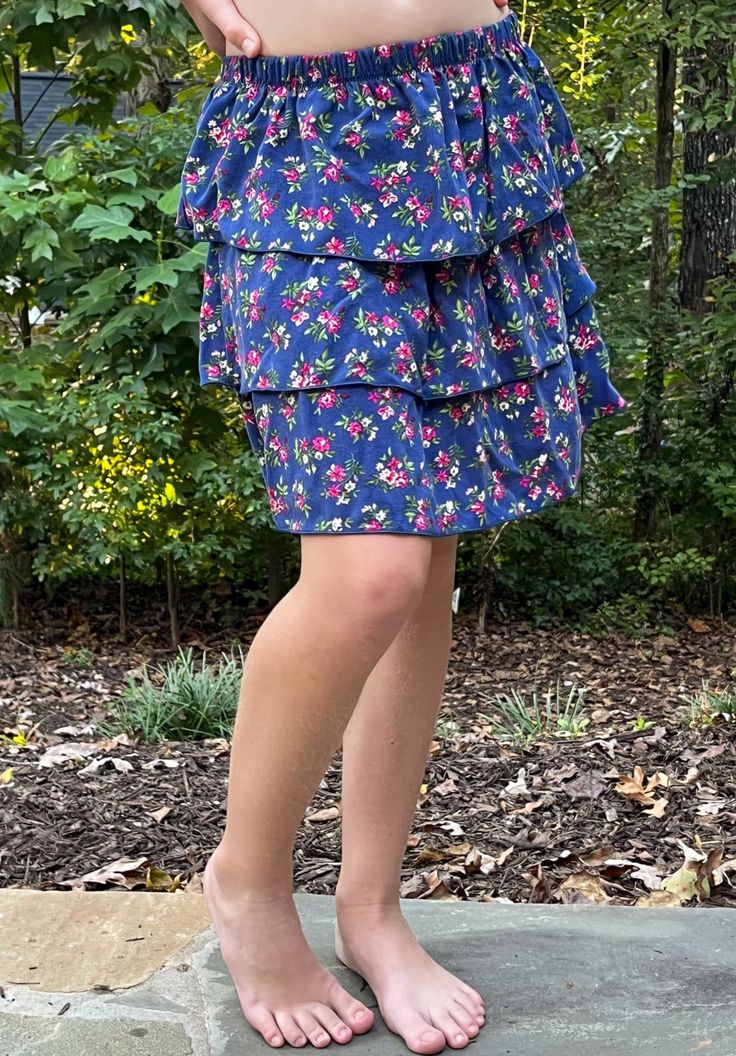 a woman standing on top of a stone slab wearing a blue skirt and pink shoes