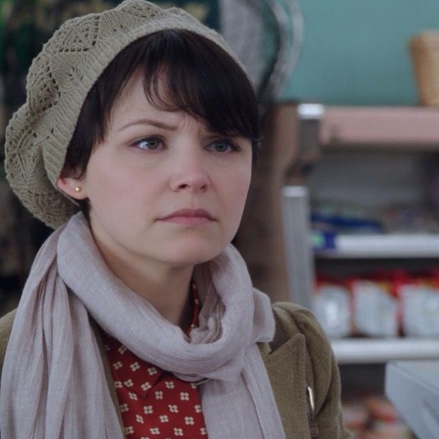 a woman wearing a hat and scarf in a kitchen