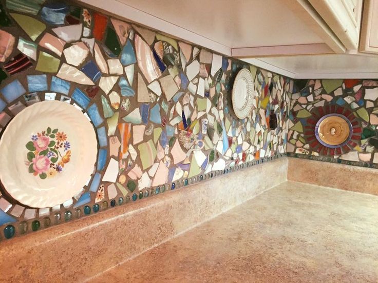 a kitchen counter topped with lots of plates and bowls on top of mosaic wall tiles