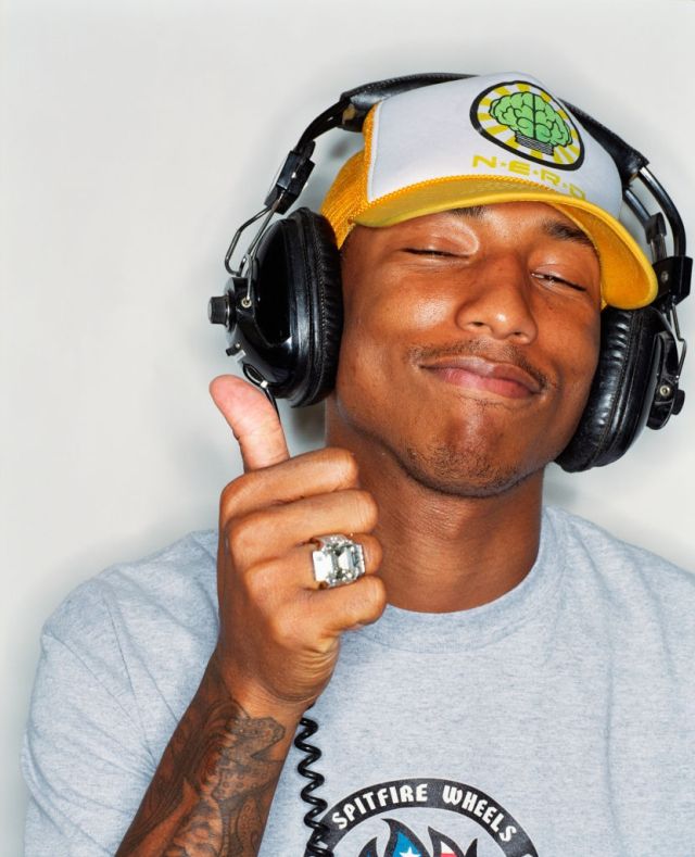 a man with headphones and a ring on his finger pointing to the side while wearing a hat