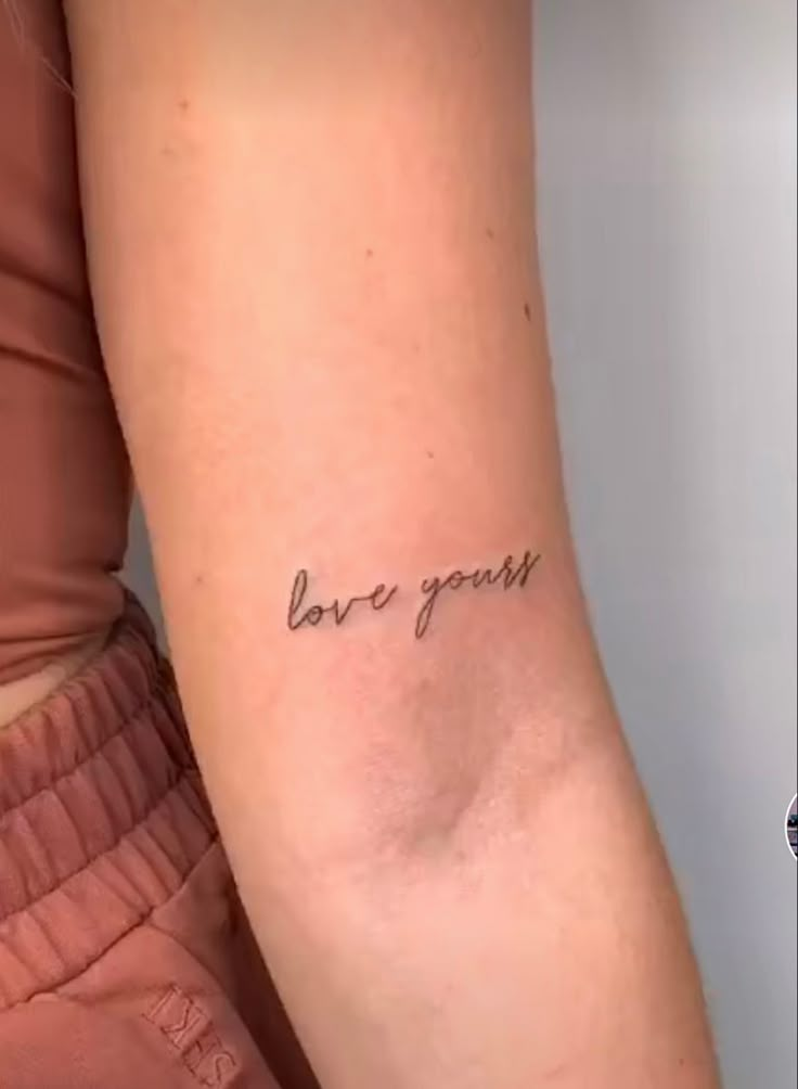 a woman's arm with the word love yourself written on it, in cursive font