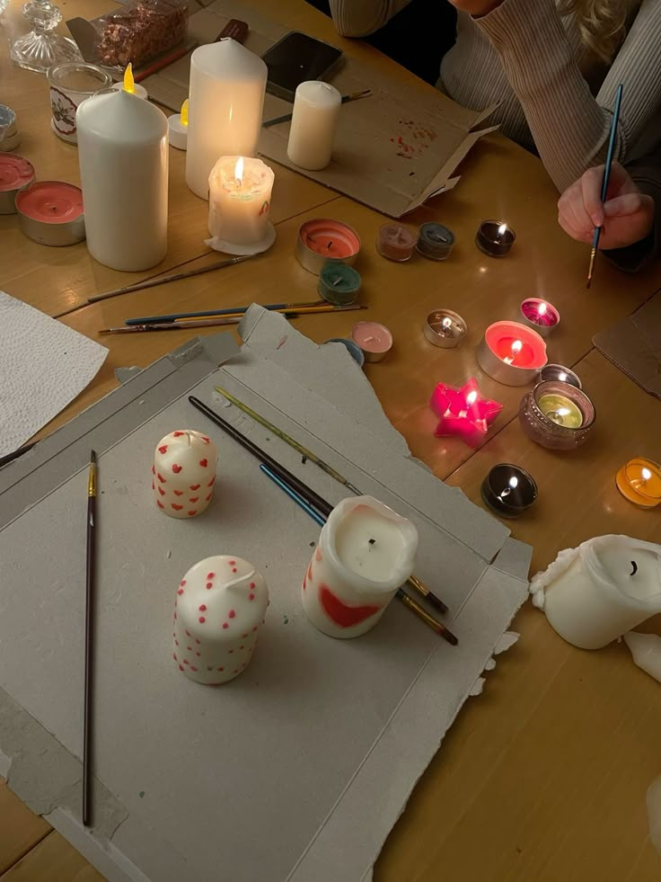 some candles are sitting on a table with paper and other crafting supplies around it