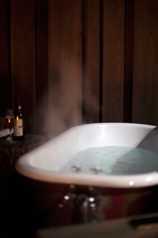 a bathtub with steam rising from it in a dark room next to a bottle