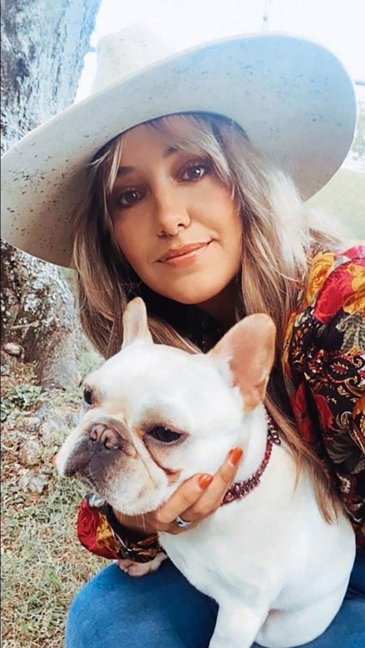 a woman in a cowboy hat holding a small dog