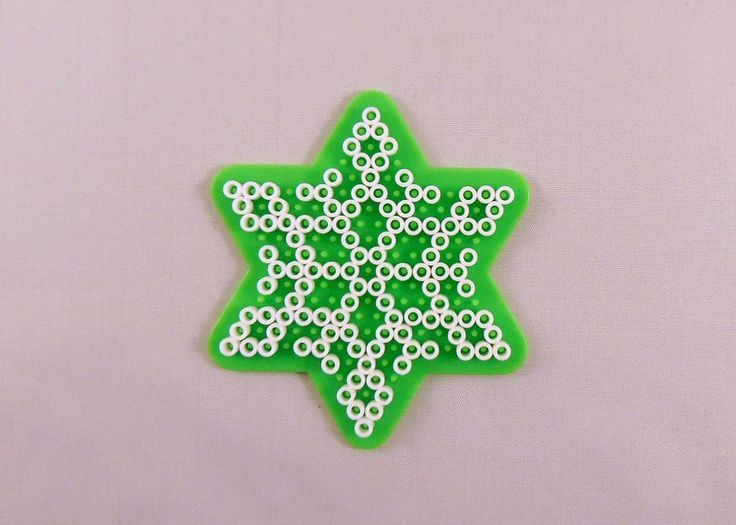 a green and white ornament sitting on top of a pink table next to a wall