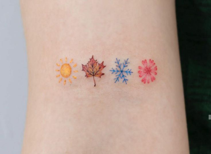 three different colored leaves on the side of a woman's arm, one with sun and snowflakes