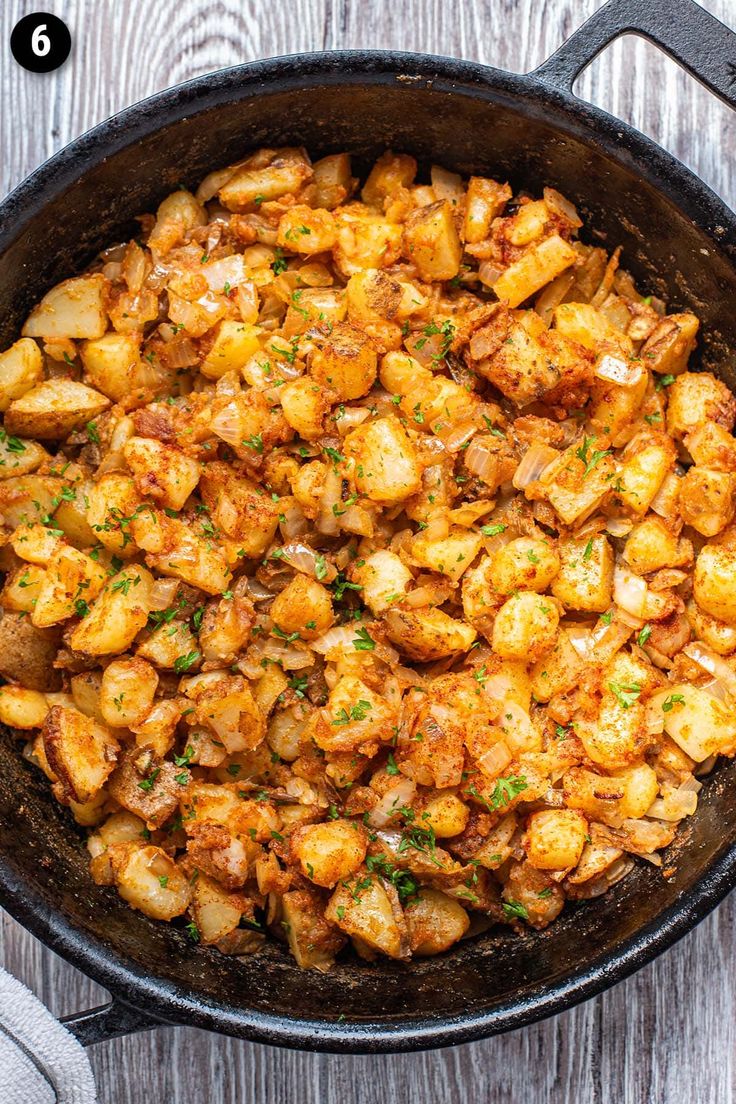 a skillet filled with potatoes on top of a wooden table