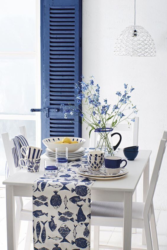 a white table topped with blue and white dishes next to a vase filled with flowers