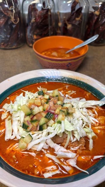 a bowl of soup is sitting on a table with other bowls and jars in the background