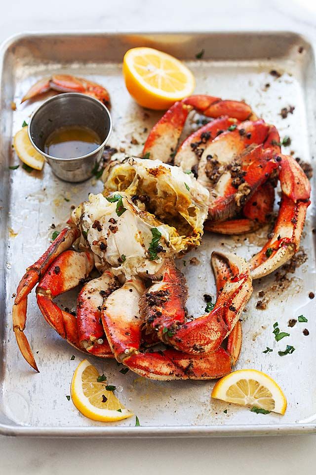 cooked lobsters on a baking sheet with lemon wedges and sauce in a bowl