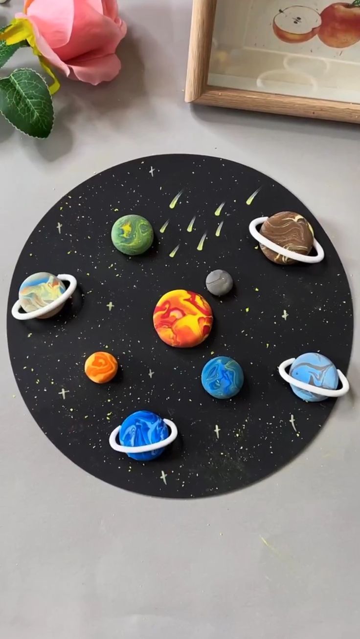 the solar system is made out of clay and plastic planets are shown in front of a pink rose