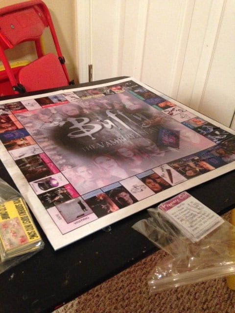 a table topped with magazines and plastic bags next to a red chair on top of a carpeted floor