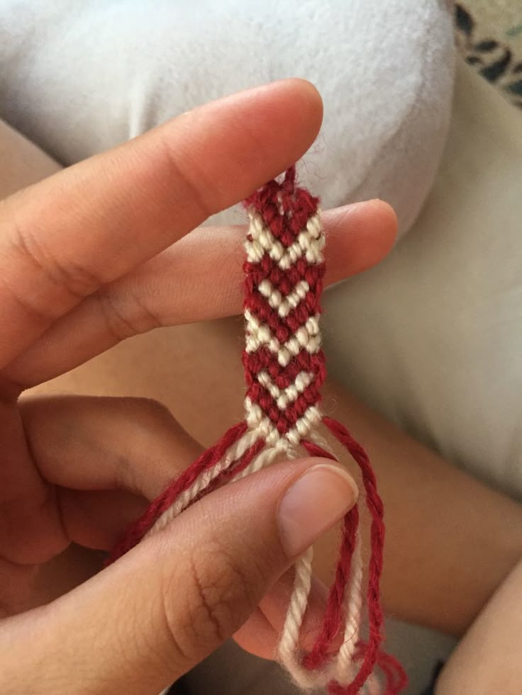 someone is holding a piece of red and white string in their left hand, while the other end of the string has been stitched together