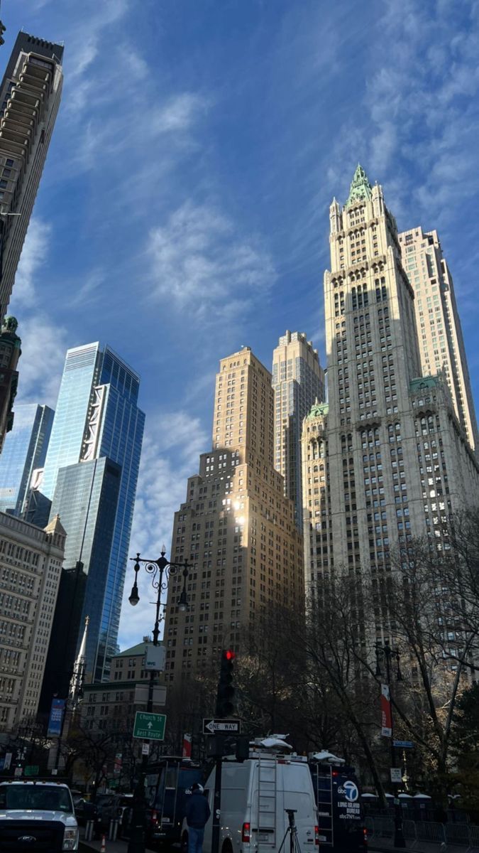 there are many tall buildings in the city on this sunny day with blue skies and white clouds