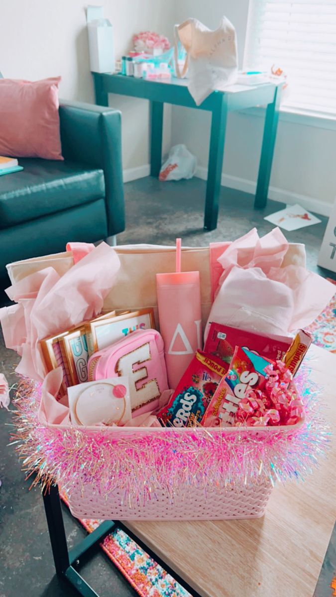 a pink basket filled with lots of items on top of a wooden table next to a couch