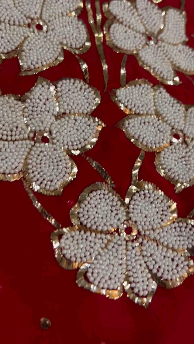 a red table topped with lots of white flowers on top of a wooden table covered in gold