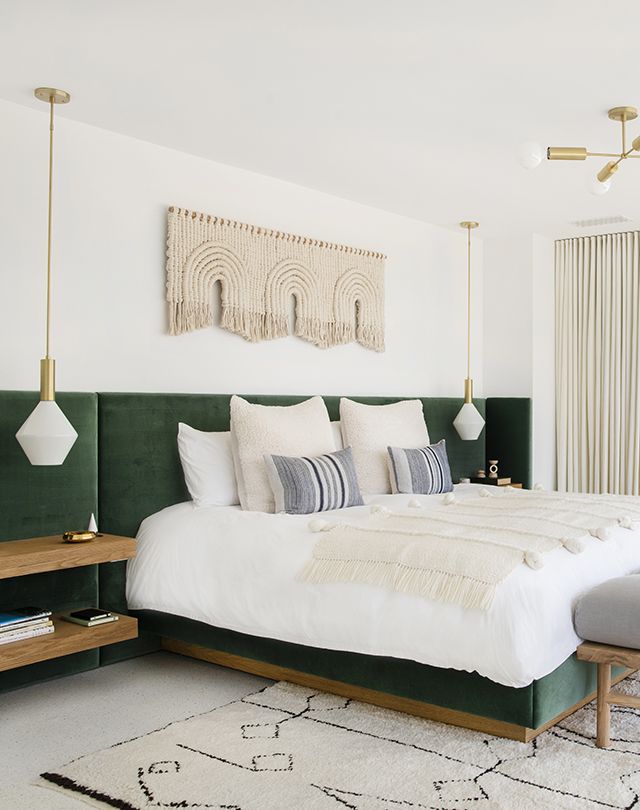 a bedroom with a large bed and green headboard on the wall next to a window