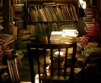 a room filled with lots of books next to a table and chair in front of a book shelf