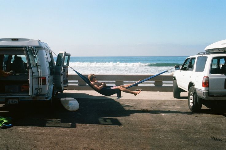 a man laying in a hammock between two vans