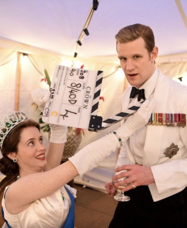 a man and woman dressed in formal wear holding up a clapper to each other