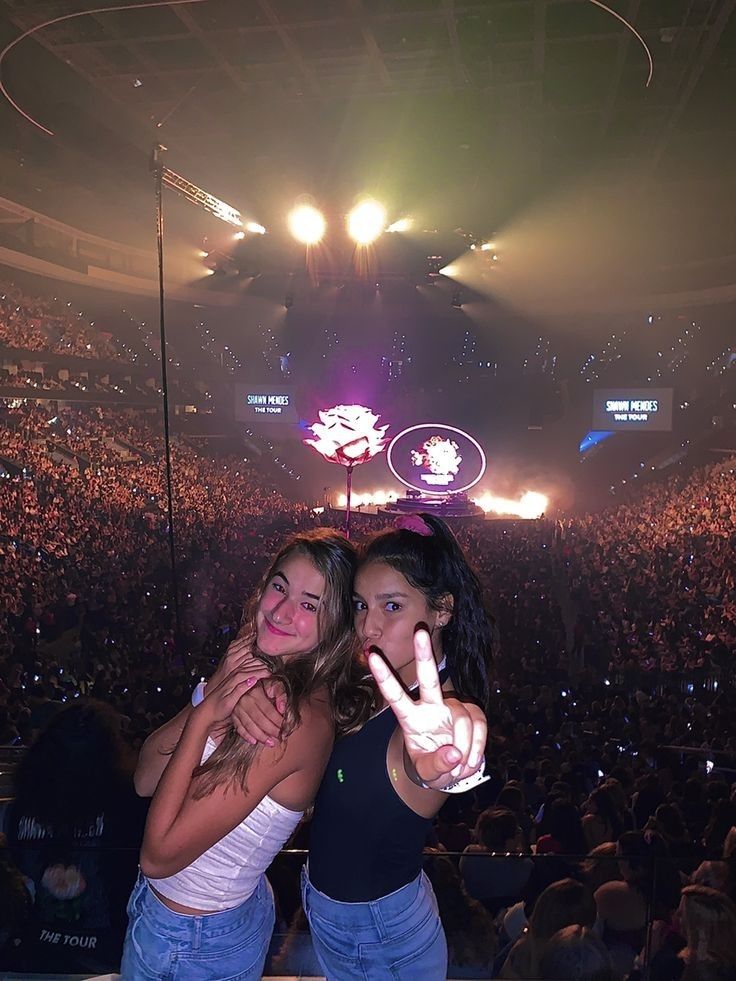 two young women standing next to each other in front of an audience at a concert