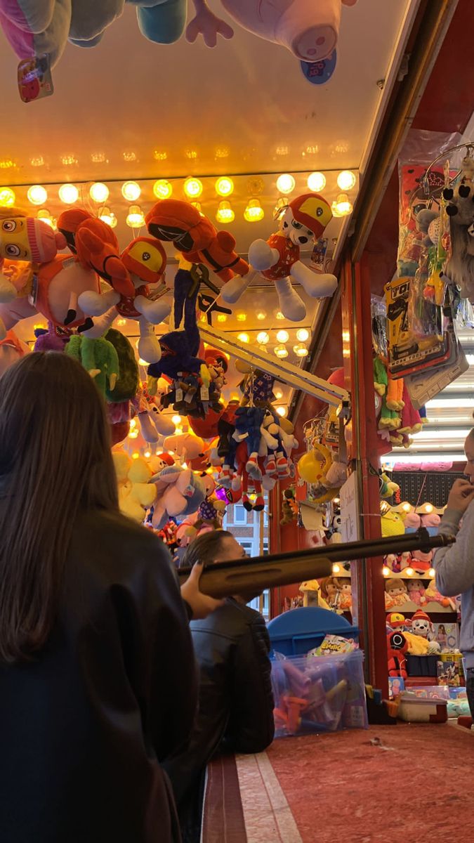 two people standing in front of a store with stuffed animals hanging from it's ceiling