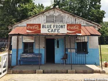 an old blue and white building with a coca - cola sign on it's roof