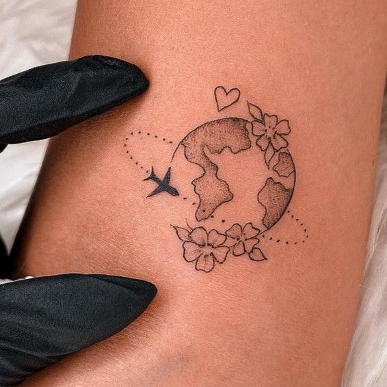 a woman's thigh with a tattoo on it and an airplane flying over the earth