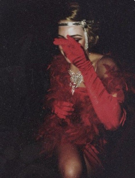 a woman with red gloves and feathers on her face