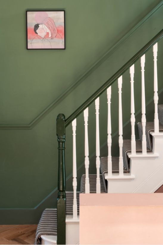 the stairs are painted green and white with a painting on the wall above them, along with carpeted flooring