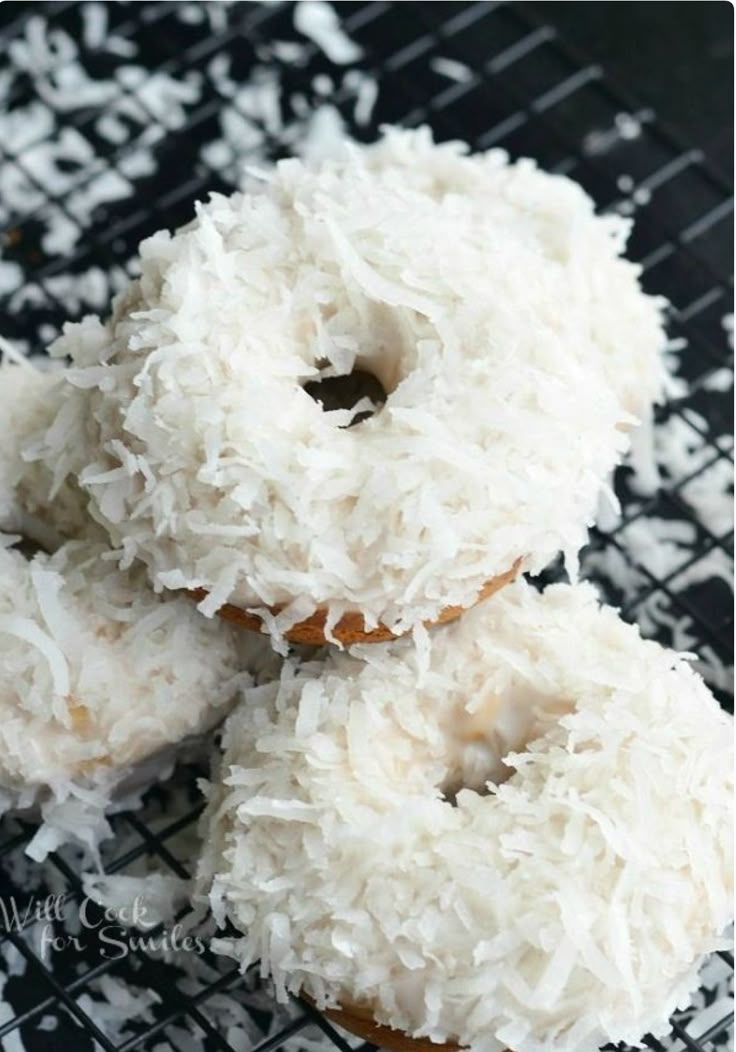 three coconut covered donuts on a cooling rack