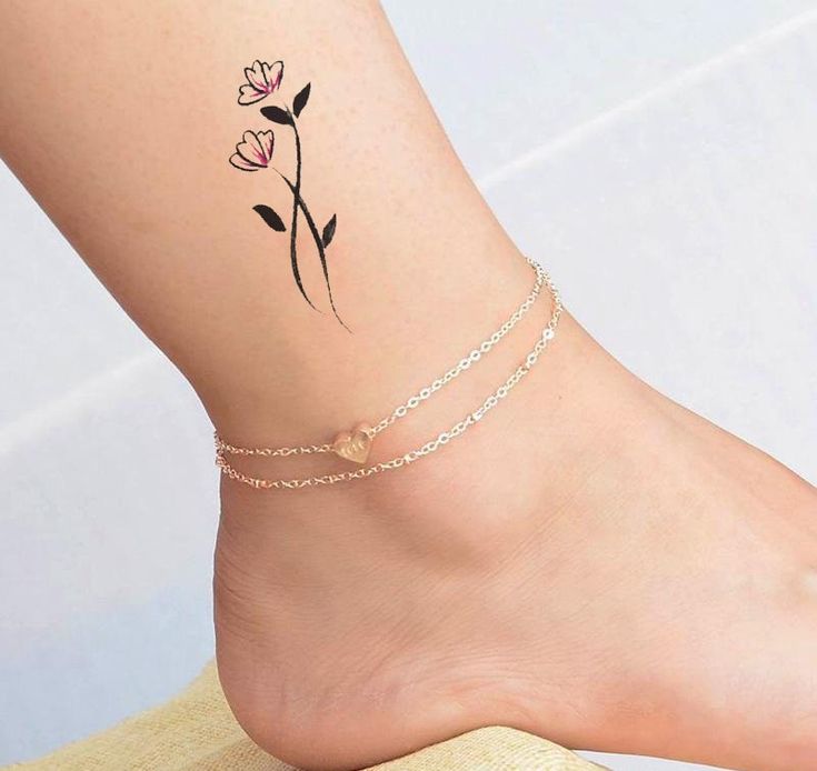 a woman's foot with a flower tattoo on the side of her leg and ankle